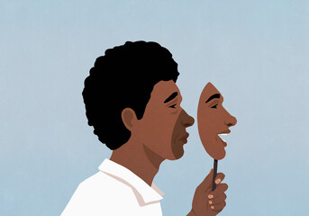 Profile of sad man holding happy mask over face against blue background
