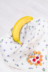 Banana and colorful candies on a floral napkin.