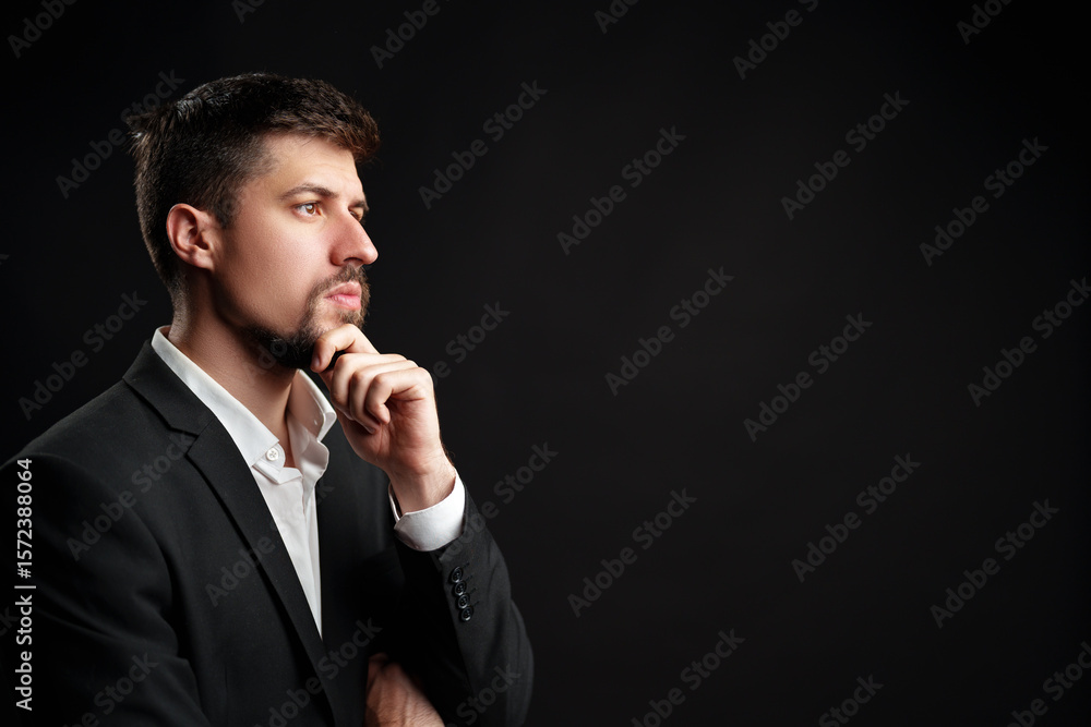 Poster man in a business suit contemplating ideas against a dark background in a studio setting