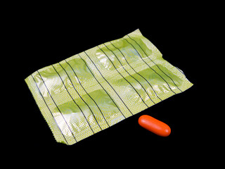 Yellow blister pack with an orange capsule on a black background.