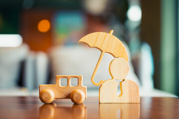Wooden car model with insurance agent model holding an umbrella for protection, concept of choosing...
