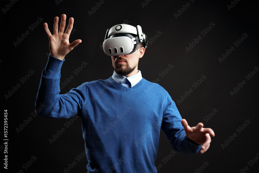 Poster man interacts with virtual reality technology in a dark studio setting experiencing immersive digita