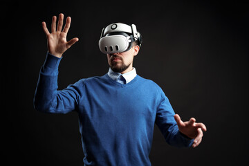 Man interacts with virtual reality technology in a dark studio setting experiencing immersive...