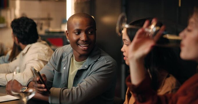 Man, friends and phone at bar for talk, drinks and reunion with app on social media at club. Person, group and happy hour in conversation, scroll or share post with smartphone on night out at pub