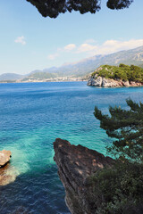 Rocky outcrop above turquoise sea with coastal mountains in Montenegro
