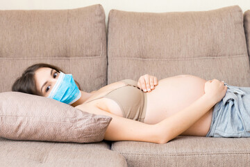 Pregnant woman is protecting herself and future child from coronavirus disease with medical mask....