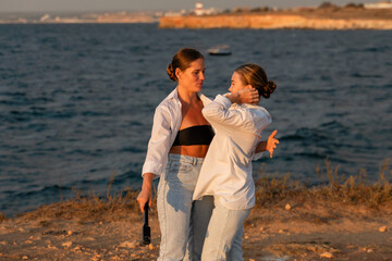 Women Friends Beach Sunset: Two women laughing on a beach at sunset.
