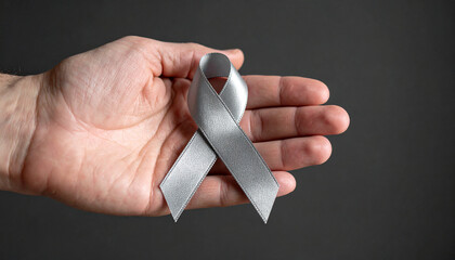Hand holding gray awareness ribbon. Brain cancer, diabetes awareness.