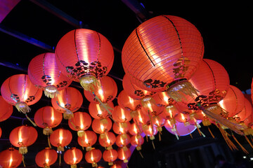 Vibrant red lanterns illuminate night sky, creating festive atmosphere. These traditional...