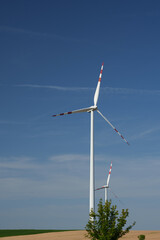 Two modern wind turbines in the countryside under a clear blue sky. Austria.