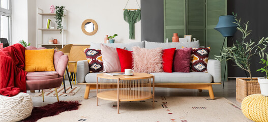 Interior of stylish living room with armchair, table and cushions on sofa