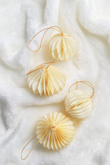 Minimal style winter holidays top view composition with New Year paper festive ornaments cream beige Christmas balls on White Faux Fur Texture background, copyspace. Neutral tones, soft shadows