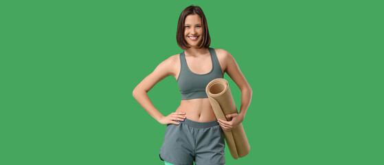 Sporty young woman with fitness mat on green background
