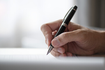 Close shot of a human hand writing something on the paper