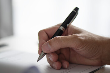 Close shot of a human hand writing something on the paper