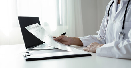 The female doctor sat and checked the patient's history and used a laptop to record patient...