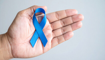Hand holding blue awareness ribbon. Child abuse prevention, colon cancer, human trafficking