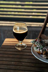 Glass of dark beer and plate with bruschetta on wooden table