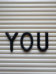 Black letters 'YOU' on a white pegboard