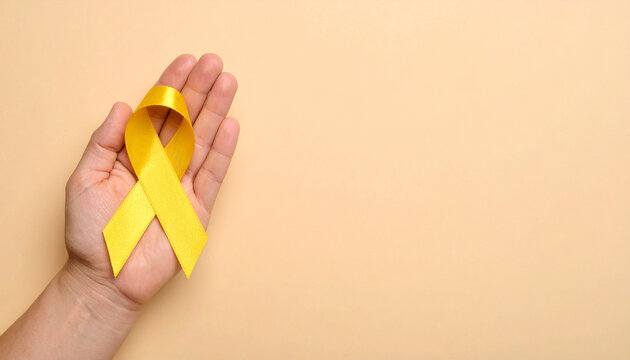 Hand holding yellow awareness ribbon. Support for military troops, suicide prevention awareness