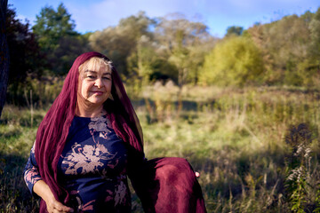 portrait of an elderly woman with gray hair in a dress and shawl in the autumn forest