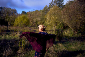 portrait of an elderly woman with gray hair in a dress and shawl in the autumn forest