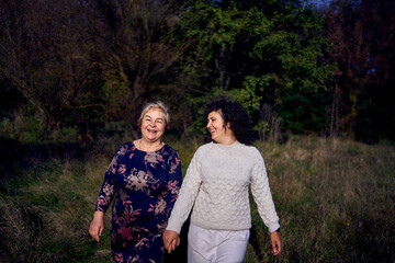 middle-aged daughter and elderly mother together on a walk in the autumn forest