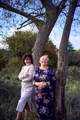 middle-aged daughter and elderly mother together on a walk in the autumn forest