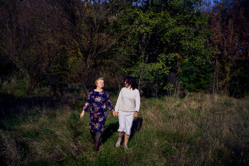 middle-aged daughter and elderly mother together on a walk in the autumn forest