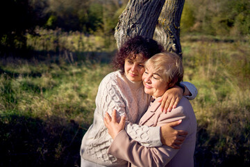 a   middle-aged daughter and elderly mother together on a walk in the autumn forest