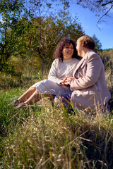 a   middle-aged daughter and elderly mother together on a walk in the autumn forest