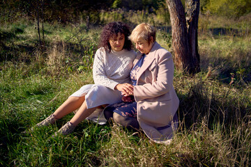a   middle-aged daughter and elderly mother together on a walk in the autumn forest