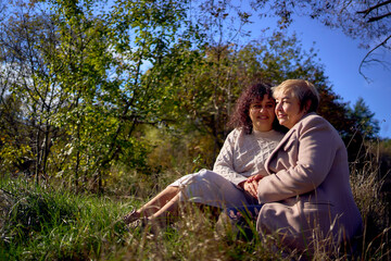 a   middle-aged daughter and elderly mother together on a walk in the autumn forest