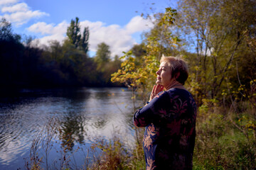     a   portrait of an elderly woman with gray hair in a dress  in the autumn forest