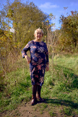     a   portrait of an elderly woman with gray hair in a dress  in the autumn forest