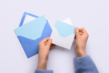 Female hands with envelopes and blank cards on white background, closeup