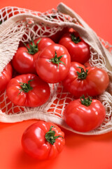 String bag with fresh tomatoes on red background