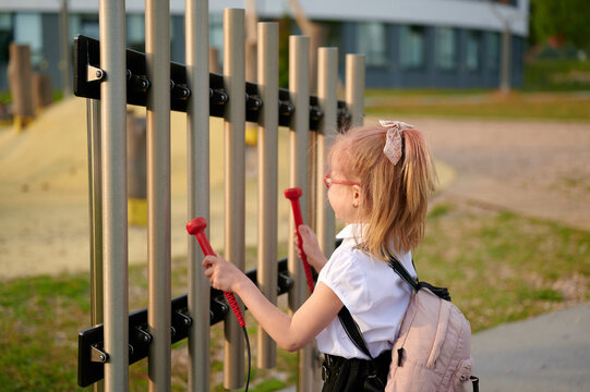 girl playing outdoor musical instrument with mallets. child exploring sound and rhythm at park. encouraging creativity and sensory development through interactive play. young musician in action
