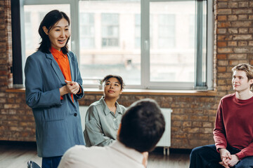 Asian businesswoman leading meeting with diverse team in modern office