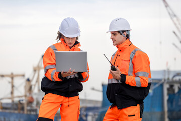 Industrial Engineers Collaborating at Port Terminal with Laptop and Walkie-Talkie, Dock Worker in Safety Uniforms Using Technology for Port Operations, Maritime Safety Engineer Working at Harbor Site