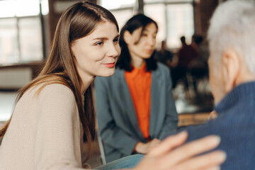 Young woman, psychologist comforting senior man during group therapy session