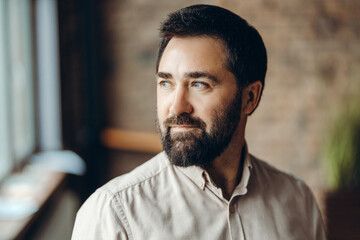 Obraz premium Pensive , handsome businessman looking away in modern office setting