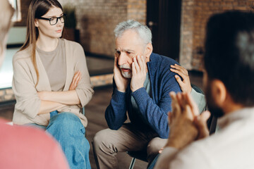 Senior man suffering from depression during group therapy session