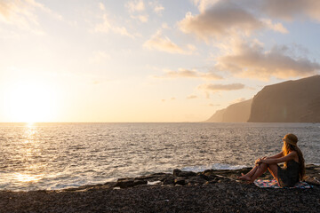 Tourist enjoying breathtaking sunset over los gigantes cliffs in tenerife, canary islands