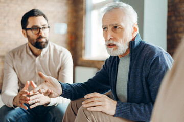 Senior man explaining something during group therapy session