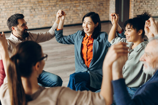 Diverse group of smiling coworkers holding hands during corporate teambuilding activity