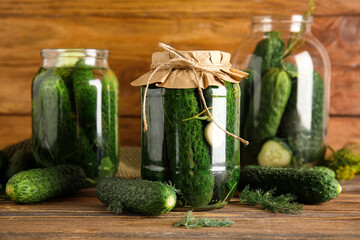 Jars with fresh and canned cucumbers on wooden background
