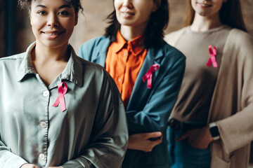 Diverse group of smiling multinational women showing pink ribbons for breast cancer awareness