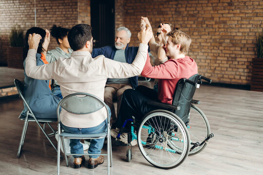 Diverse group of multinational people joining hands in support and inclusivity during therapy session