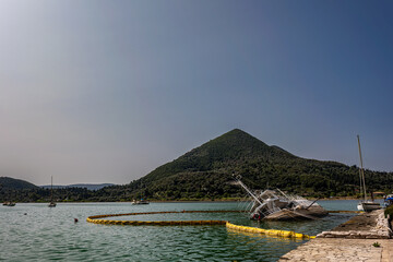 Sunken boat near shore with green hills in background